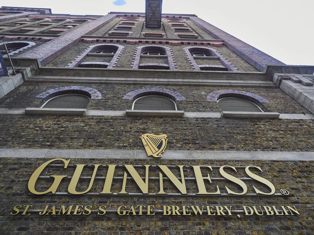 Exterior view of Guinness Storehouse in Dublin showcasing the iconic brewery sign and historic brick building, emphasizing brand heritage and quality brewing.